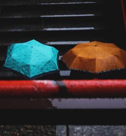 A blue and an orange umbrella in the rain